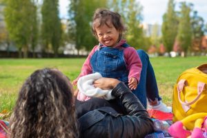 Smiling mother and child with Down syndrome enjoy picnic, supporting children with higher needs in Western Australia.