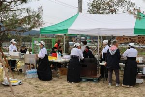 Korean outdoor market, traditional attire, food prep in Australia.