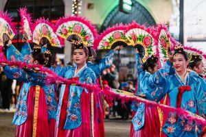 Korean Australian cultural exchange: Asian women in traditional costumes dance outdoors.