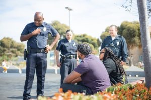 Police officers interacting with individuals on the street in a diverse setting, showcasing community engagement.